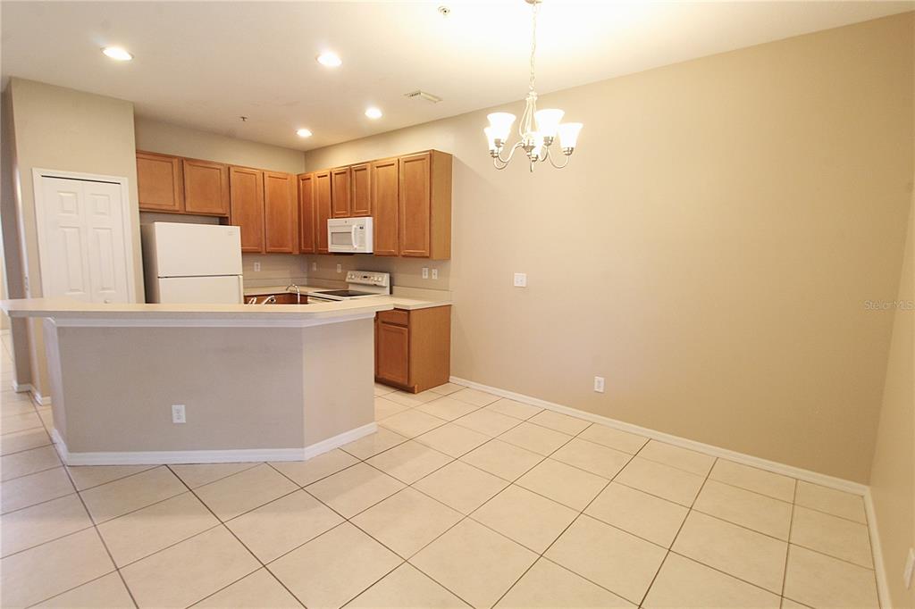A kitchen with light-colored tile flooring, wooden cabinets, and a breakfast bar — 4011 BURLWOOD ROAD, SARASOTA, FL