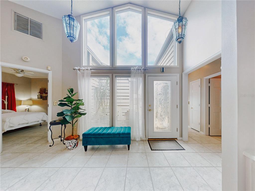 A bright entryway features tile flooring, a teal bench, a front door, and high windows — 102 COUNTRY PLACE, SANFORD, FL