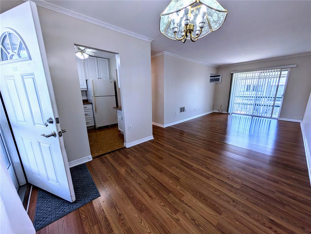 An interior view shows a living area with wood-look flooring, a chandelier, and an adjacent kitchen — 1840 SUNNY DRIVE UNIT D-36, BRADENTON, FL