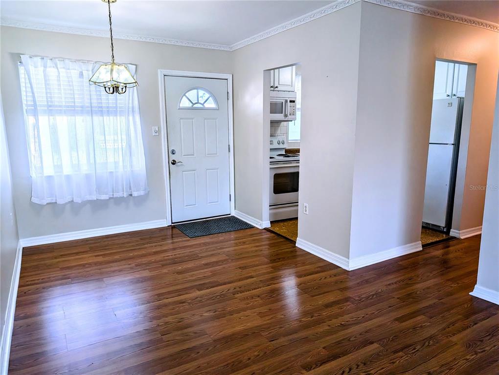 A dining area with hardwood floors, a white front door, and an adjacent kitchen — 1840 SUNNY DRIVE UNIT D-36, BRADENTON, FL