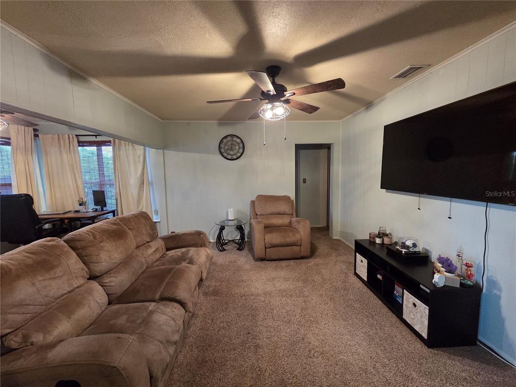 A living room features a brown sofa, a recliner, a television, and a ceiling fan — 124 E F ST, FROSTPROOF, FL