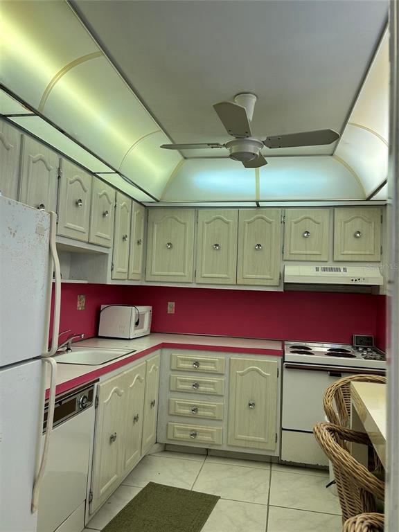 A kitchen features light wood cabinets, a pink backsplash, white appliances, and a ceiling fan — 4090 NW 42ND AVENUE UNIT 105, FORT LAUDERDALE, FL