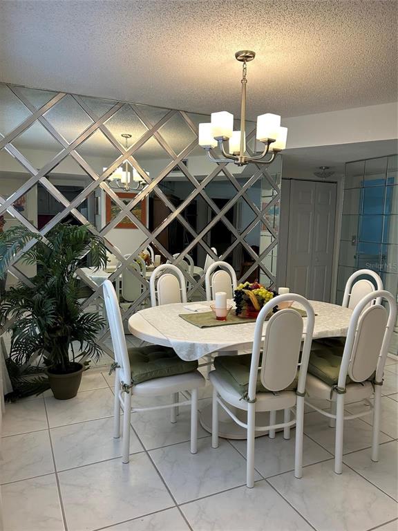 A dining room features a round table, white chairs, and a large mirrored wall — 4090 NW 42ND AVENUE UNIT 105, FORT LAUDERDALE, FL