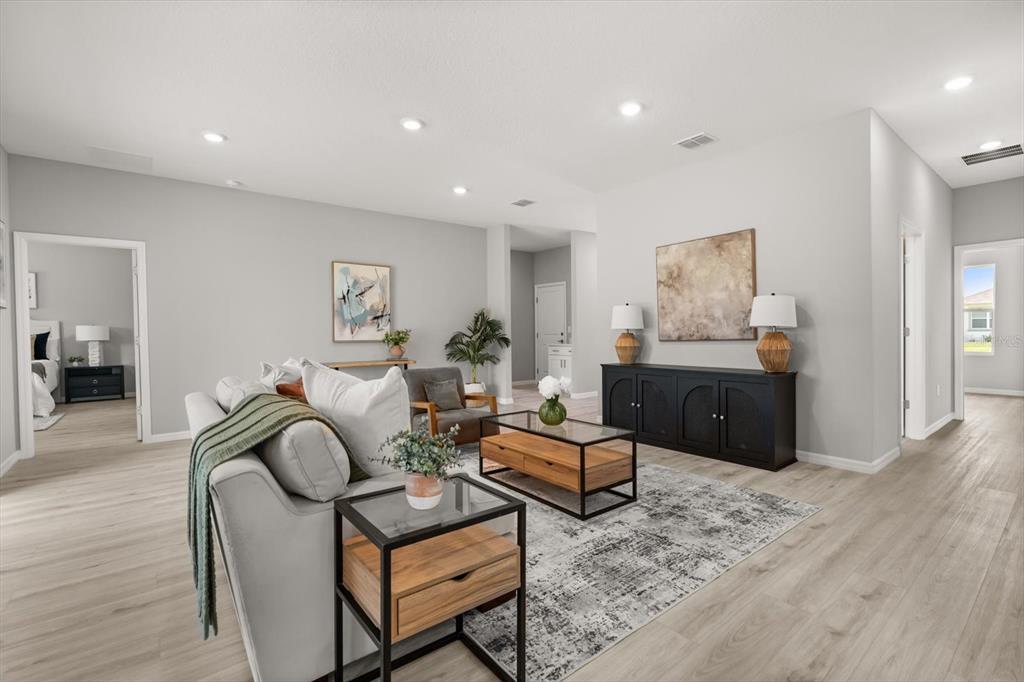 A living room features light wood-look flooring, a grey sofa, and a black console table — 5336 COLUMBUS BOULEVARD, SEBRING, FL