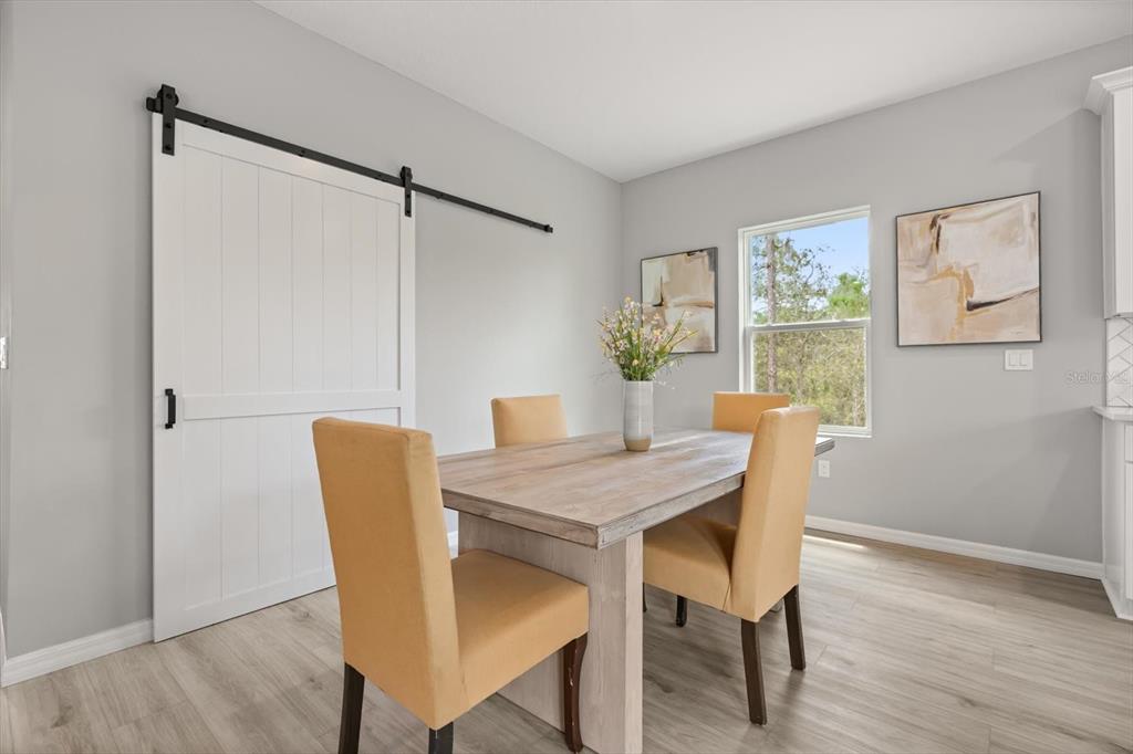 A dining room features a wooden table, four yellow chairs, and a white sliding barn door — 5336 COLUMBUS BOULEVARD, SEBRING, FL