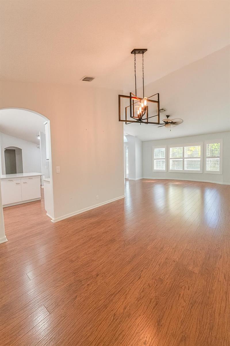 An open dining area with wood-look flooring, a metal chandelier, and an arched entryway — 16215 121st Terrace N, Jupiter FL 33478, JUPITER, FL