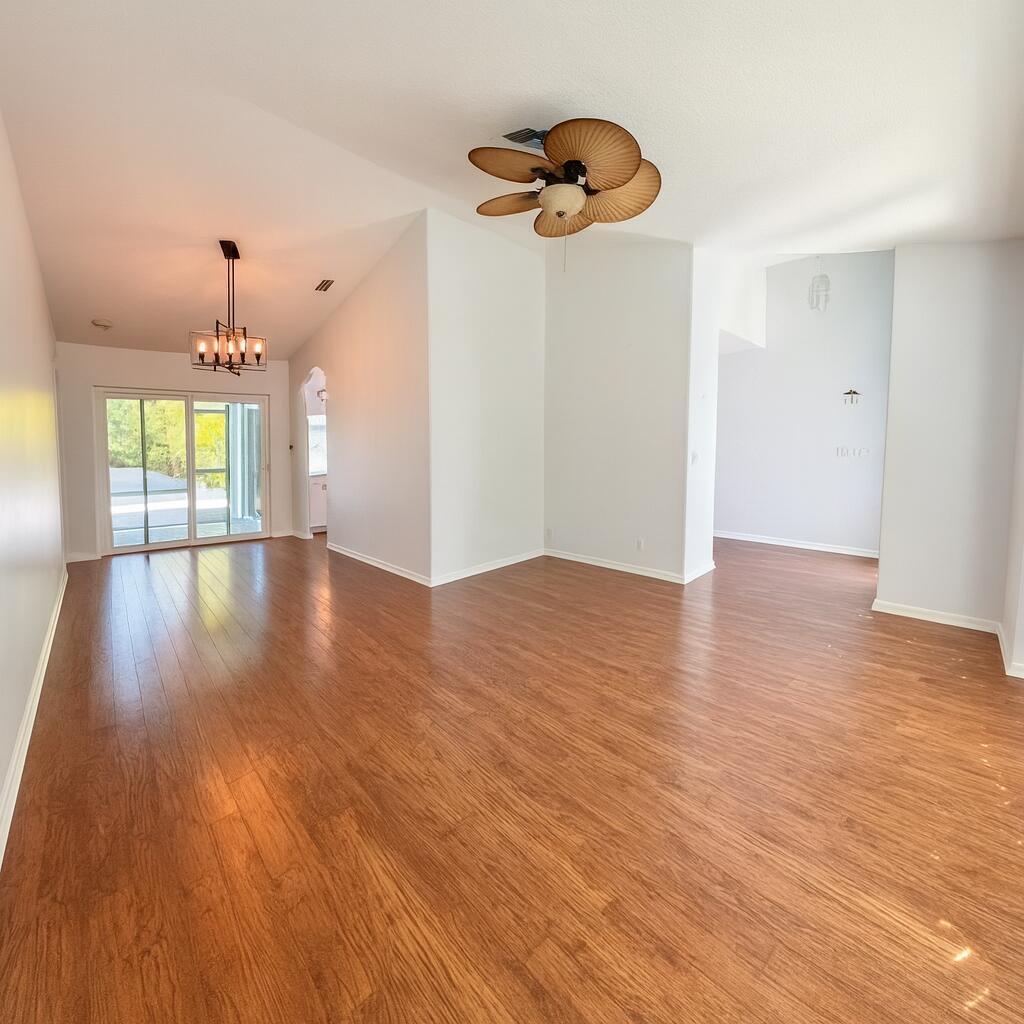 An empty living area features wood-look flooring, a vaulted ceiling, a ceiling fan, and chandelier — 16215 121st Terrace N, Jupiter FL 33478, JUPITER, FL