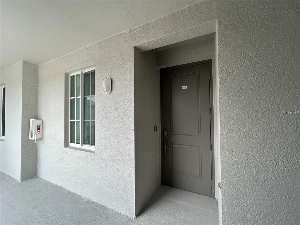 A gray door with the number 403 is set into a textured, light-colored exterior wall — 12240 WELLEN GOLF STREET UNIT 403, VENICE, FL