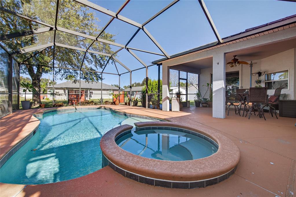A screened-in patio features a swimming pool, a raised hot tub, and a dining area — 42 BUFFALO BILL DRIVE, PALM COAST, FL