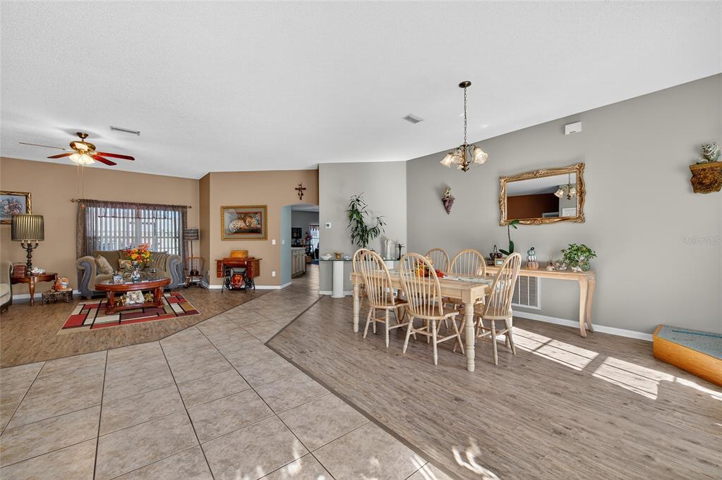 A dining area and living room with tile and wood-look flooring and a ceiling fan — 42 BUFFALO BILL DRIVE, PALM COAST, FL