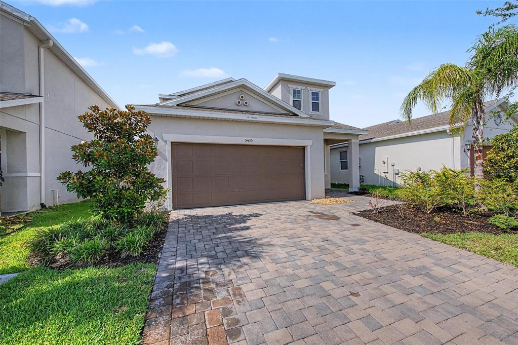 A tan house with a brown garage door and a paved driveway under a blue sky — 5435 BUNGALOW GROVE COURT, PALMETTO, FL