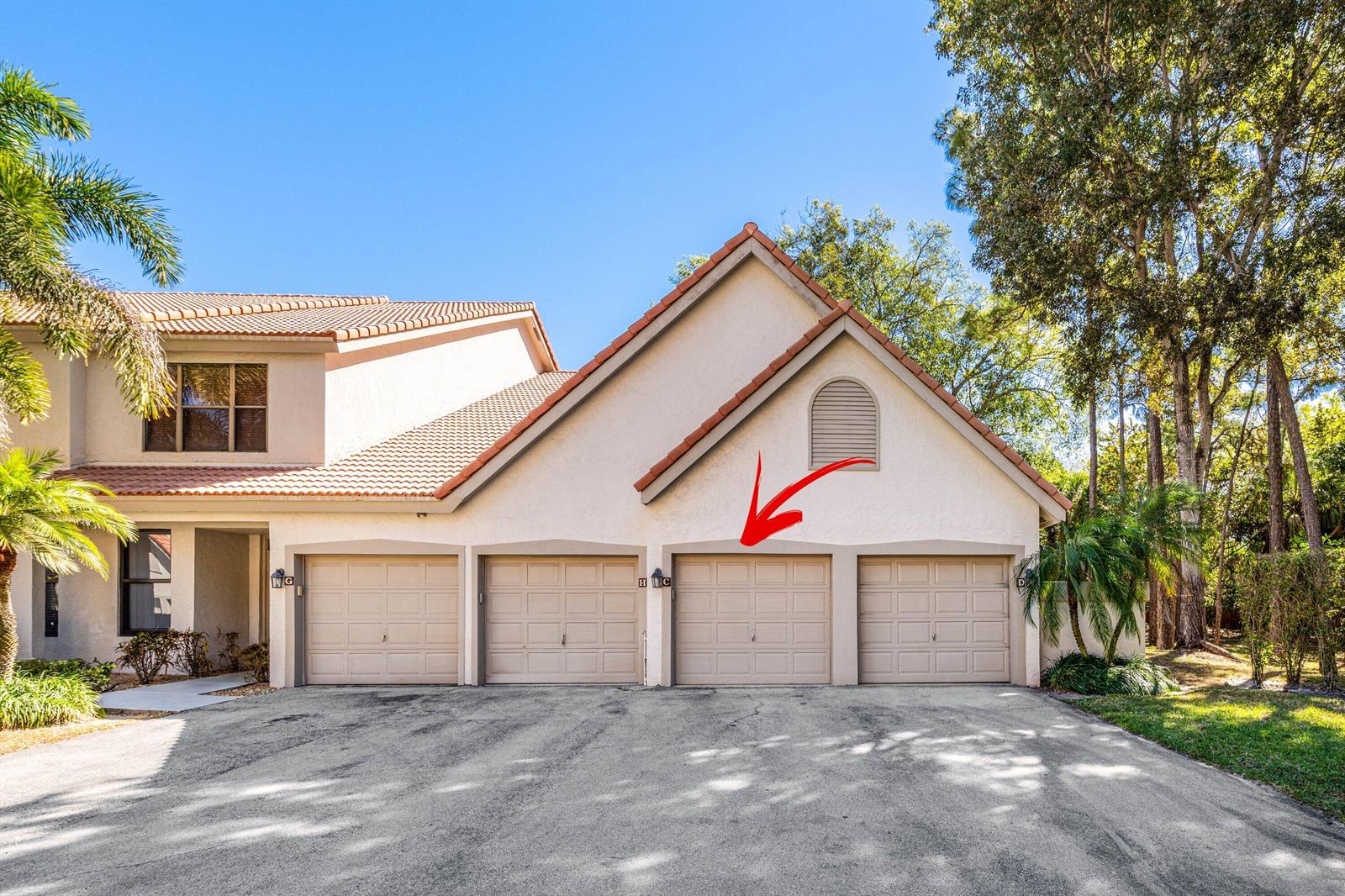 The exterior of a multi-unit building features four garage doors and a tiled roof — 5780 Coach House Circle # C, Boca Raton FL 33486, BOCA RATON, FL