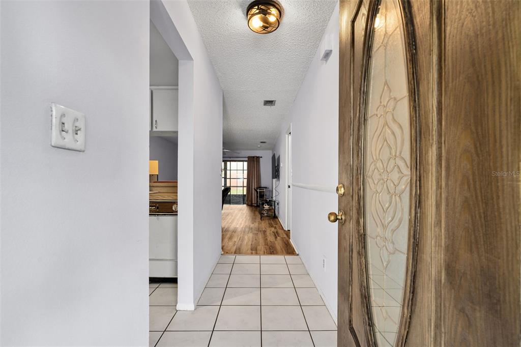 A tiled entryway leads into a living area with wood-look flooring and a glass door — 2008 SUNSET GROVE LANE, CLEARWATER, FL