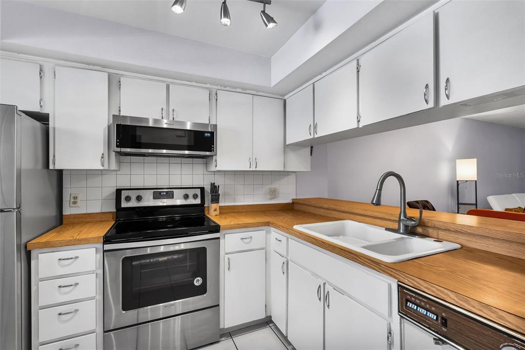 A kitchen with white cabinets, stainless steel appliances, and wood-look laminate countertops — 2008 SUNSET GROVE LANE, CLEARWATER, FL