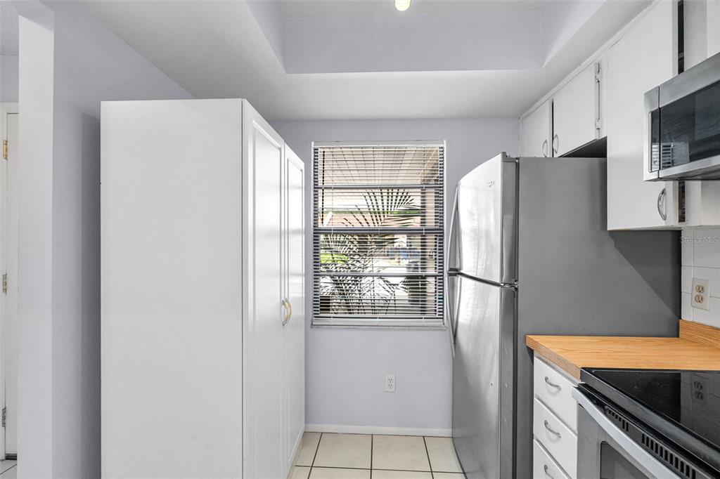 A kitchen features white cabinets, a stainless steel refrigerator, and a window with blinds — 2008 SUNSET GROVE LANE, CLEARWATER, FL