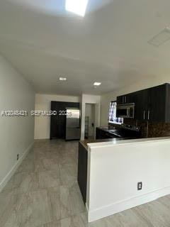 A kitchen with dark cabinets, stainless steel appliances, and light-colored tile flooring — 3411 NW 9th Ct # B, Miami FL 33127, MIAMI, FL