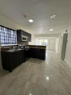 A kitchen with dark cabinets, stainless steel appliances, and light-colored tile flooring — 3411 NW 9th Ct # B, Miami FL 33127, MIAMI, FL