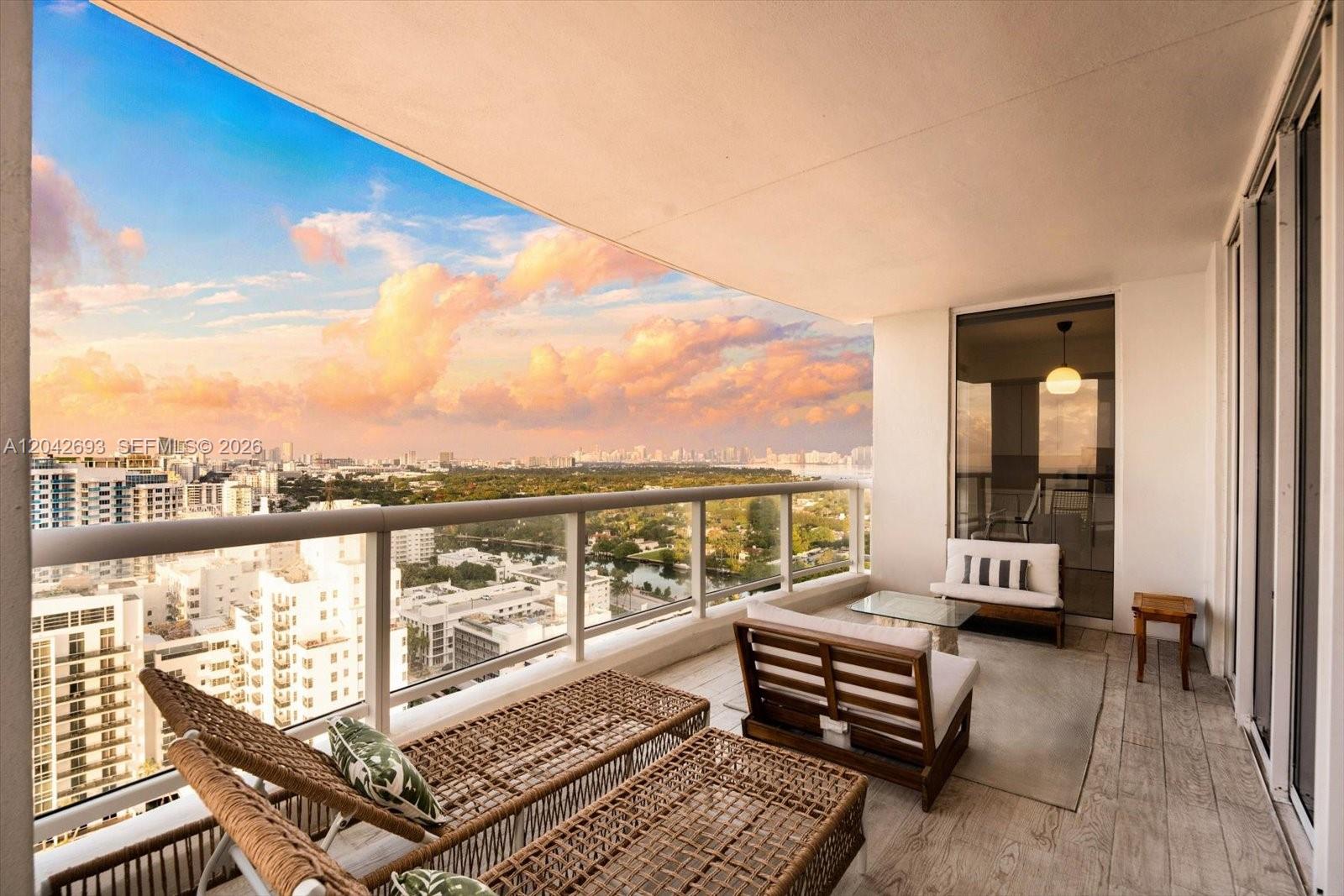 A balcony with outdoor furniture overlooks a city skyline at sunset — 4201 Collins Ave # 2301, Miami Beach FL 33140, MIAMI BEACH, FL