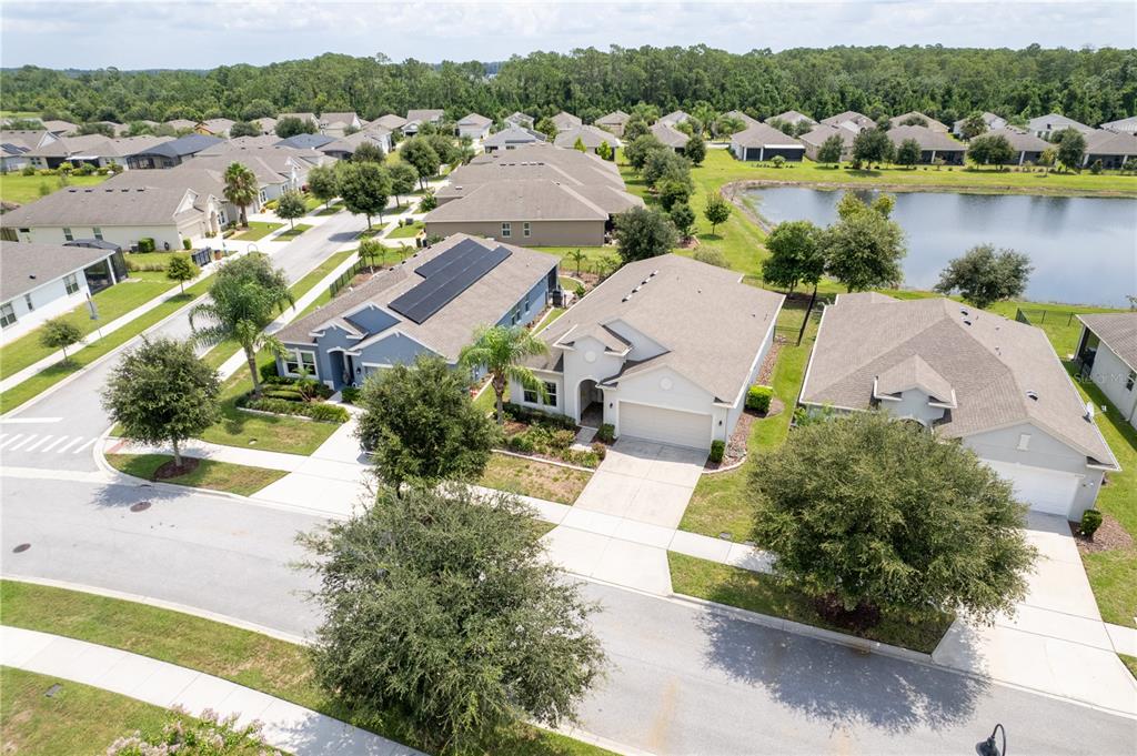 An aerial view of a suburban neighborhood featuring houses with driveways and a nearby pond — 3331 SAGEBRUSH STREET, HARMONY, FL