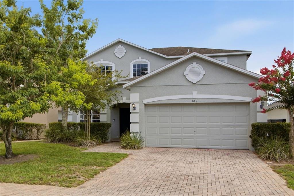 A two-story house with a gray stucco exterior, a two-car garage, and a paver driveway — 612 HIGHGATE PARK BOULEVARD, DAVENPORT, FL