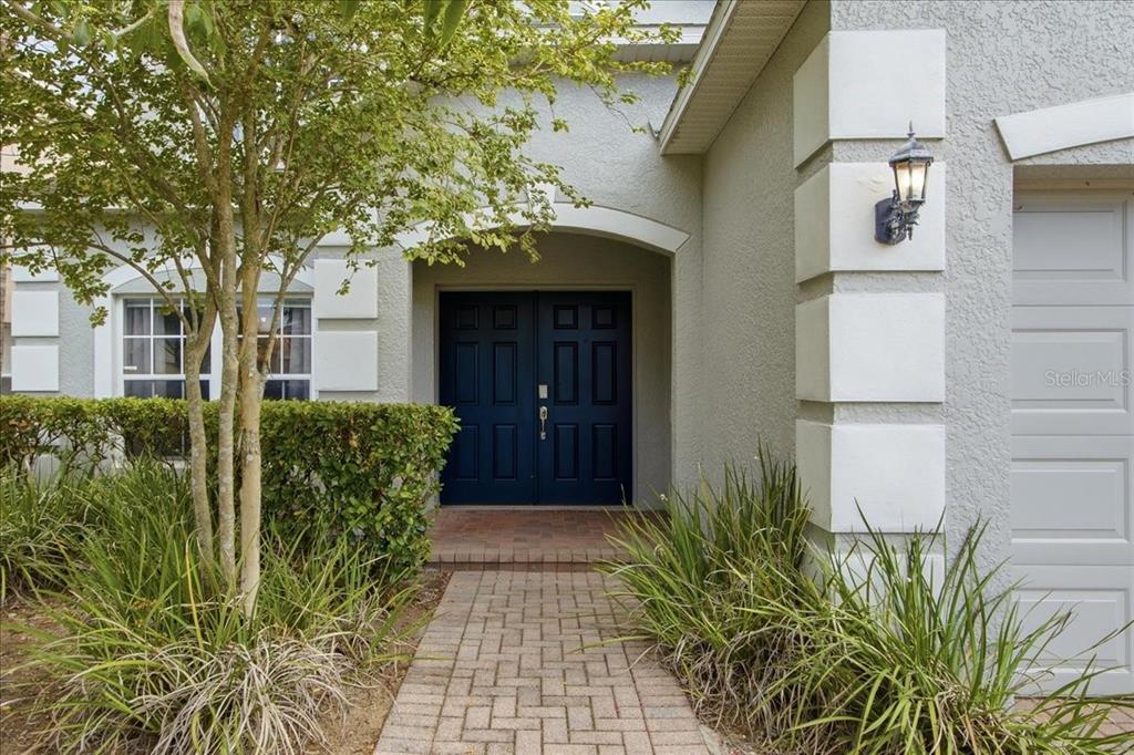 A paved walkway leads to a dark blue double front door under a covered entryway — 612 HIGHGATE PARK BOULEVARD, DAVENPORT, FL