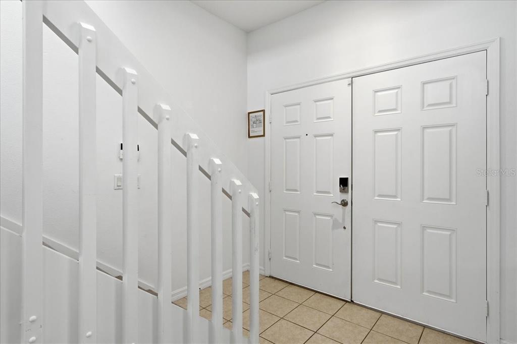 An entryway features a white double door, tiled flooring, and a staircase with white railings — 612 HIGHGATE PARK BOULEVARD, DAVENPORT, FL