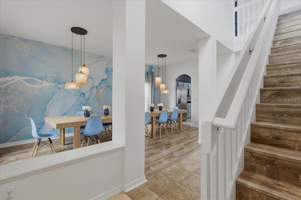 A dining area with a blue marble-patterned wall mural sits beside a wooden staircase — 612 HIGHGATE PARK BOULEVARD, DAVENPORT, FL