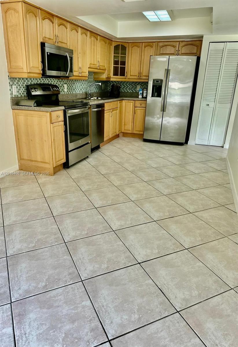 A kitchen features light wood cabinets, stainless steel appliances, and beige tile flooring — 14530 SW 142nd Ct Cir, Miami FL 33186, MIAMI, FL