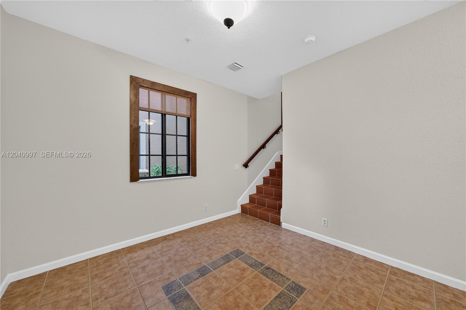 A room with beige walls, tile flooring, a window with a wood frame, and stairs — 2767 Kinsington Cir # 4, Weston FL 33332, WESTON, FL