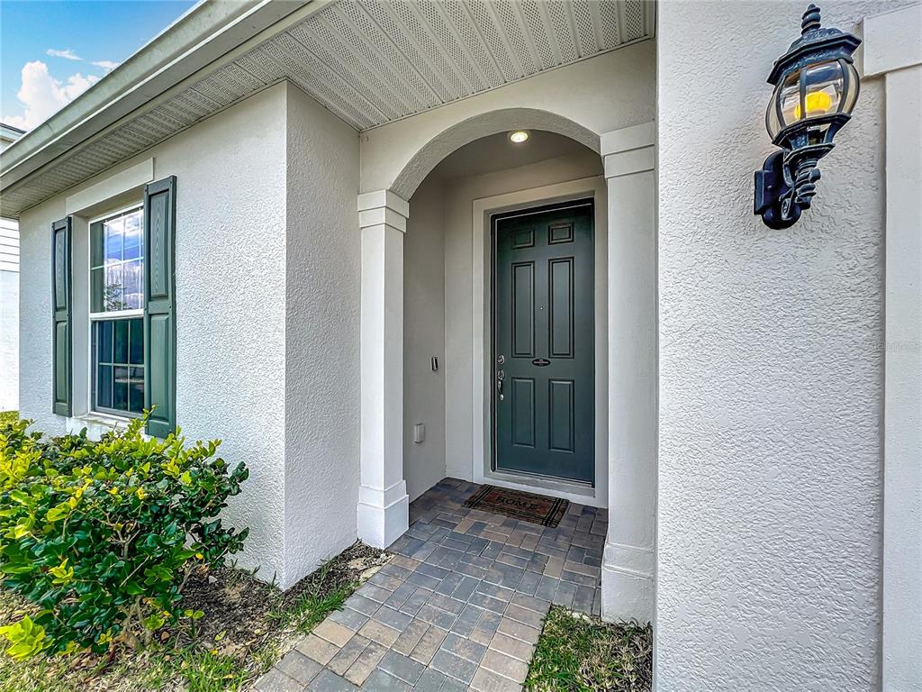 A paved walkway leads to a covered front entryway with a dark green door — 2610 HILLTOP LOOP, APOPKA, FL