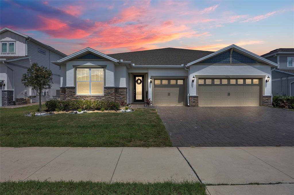 A single-story house with a stone-accented facade, a three-car garage, and a paved driveway — 3286 MAINSAIL COURT, WINTER GARDEN, FL
