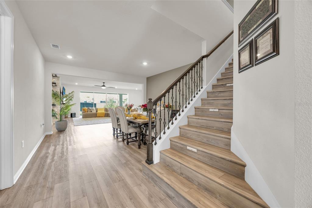 A view of a home interior featuring wood-look flooring, a staircase with iron railings, and dining area — 3286 MAINSAIL COURT, WINTER GARDEN, FL