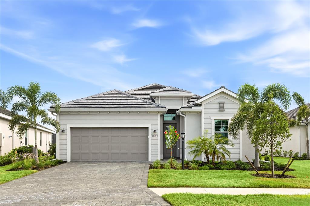 A single-story house with a gray garage, light siding, and palm trees in the front yard — 19108 CHERRYSTONE WAY, LAKEWOOD RANCH, FL
