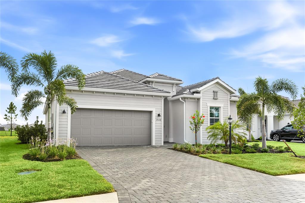A single-story house with a gray garage, light siding, and palm trees in the yard — 19108 CHERRYSTONE WAY, LAKEWOOD RANCH, FL