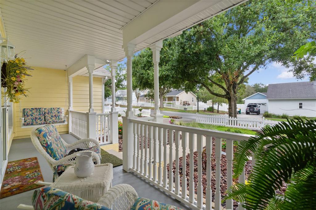 A covered front porch with white railings, wicker furniture, and a view of the neighborhood — 1622 LAUREL WAY, TAVARES, FL