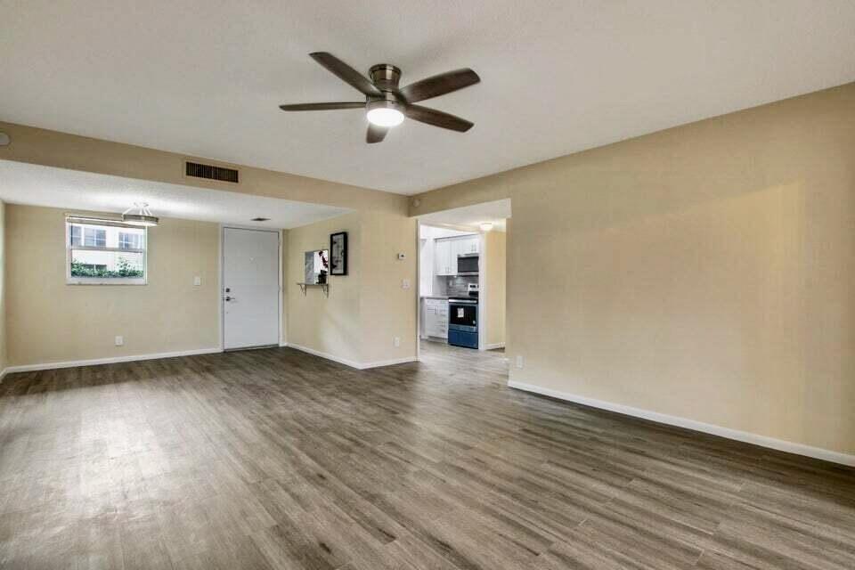 An open-concept living area features light-colored walls, wood-look flooring, a ceiling fan, and a kitchen — 705 Lori Drive # 104, Palm Springs FL 33461, PALM SPRINGS, FL