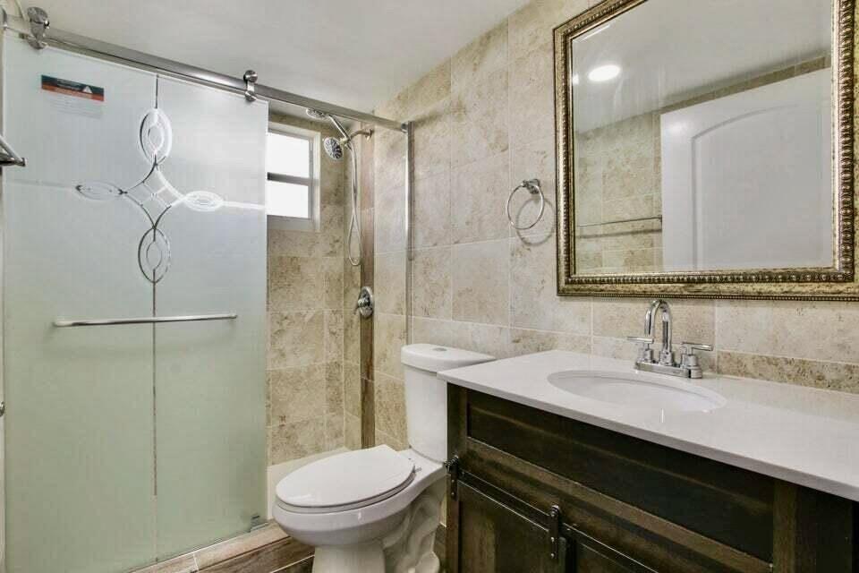 A bathroom features a glass-enclosed shower, a white toilet, and a dark wood vanity — 705 Lori Drive # 104, Palm Springs FL 33461, PALM SPRINGS, FL