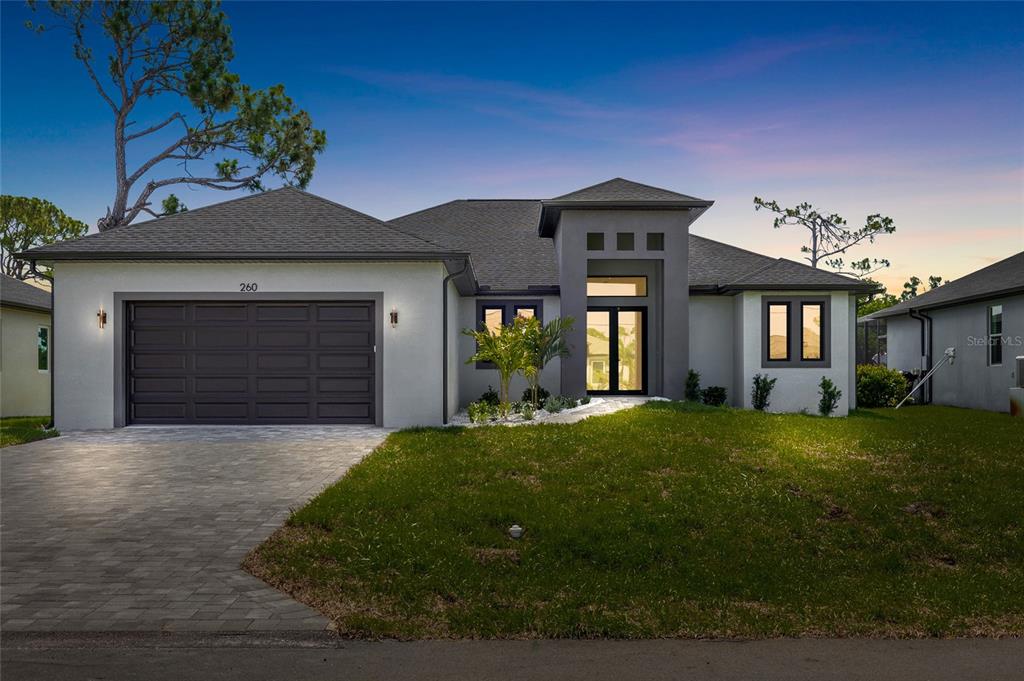 A single-story house with a gray stucco exterior, a two-car garage, and a paved driveway — 260 TOURNAMENT ROAD, ROTONDA WEST, FL