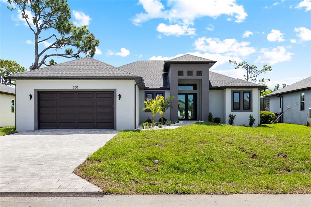A modern single-story house with a gray stucco exterior, dark trim, and a paved driveway — 260 TOURNAMENT ROAD, ROTONDA WEST, FL