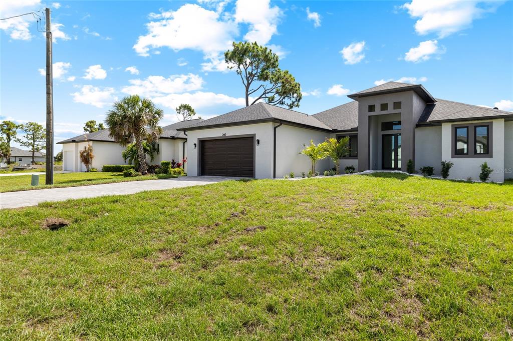A single-story house with a gray exterior, a dark garage door, and a paved driveway — 260 TOURNAMENT ROAD, ROTONDA WEST, FL