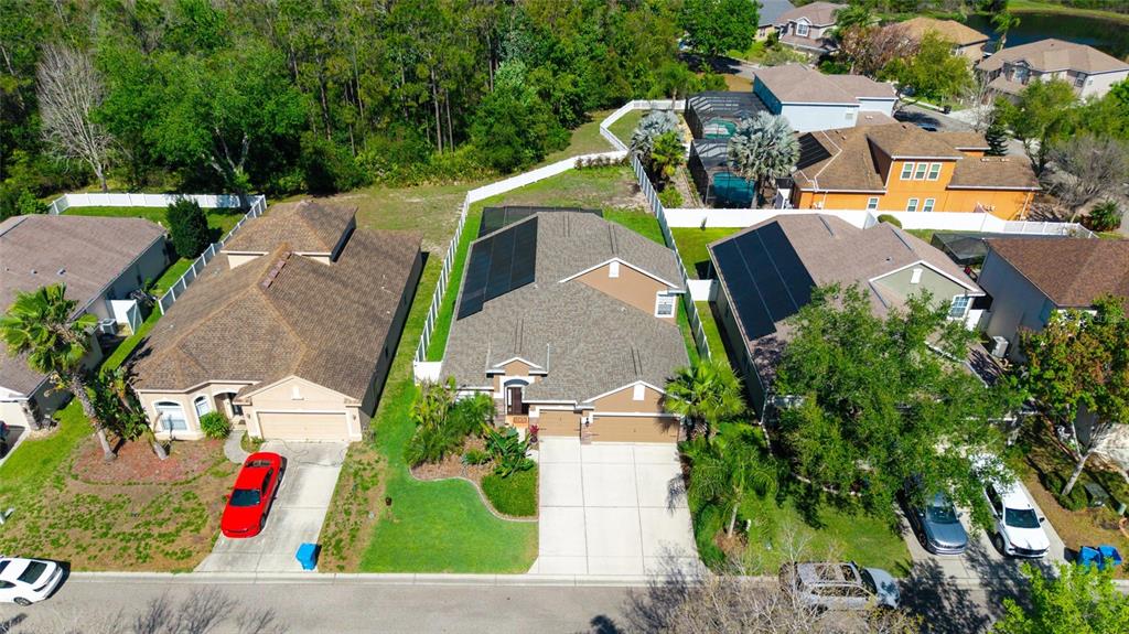An aerial view shows suburban houses with solar panels, driveways, and surrounding green spaces — 11129 OYSTER BAY CIRCLE, NEW PORT RICHEY, FL
