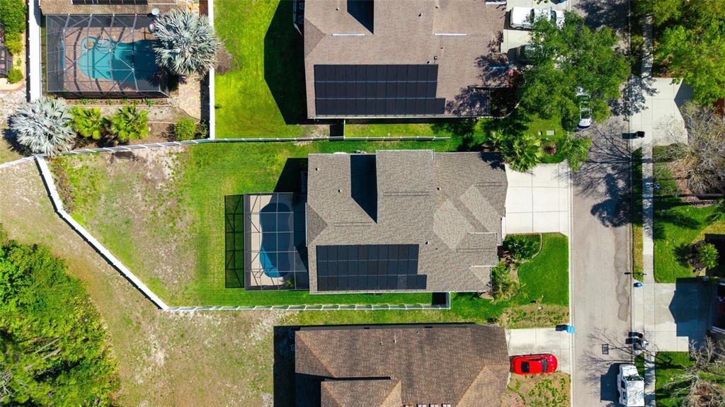 An aerial view shows three suburban houses with solar panels and backyard swimming pools — 11129 OYSTER BAY CIRCLE, NEW PORT RICHEY, FL