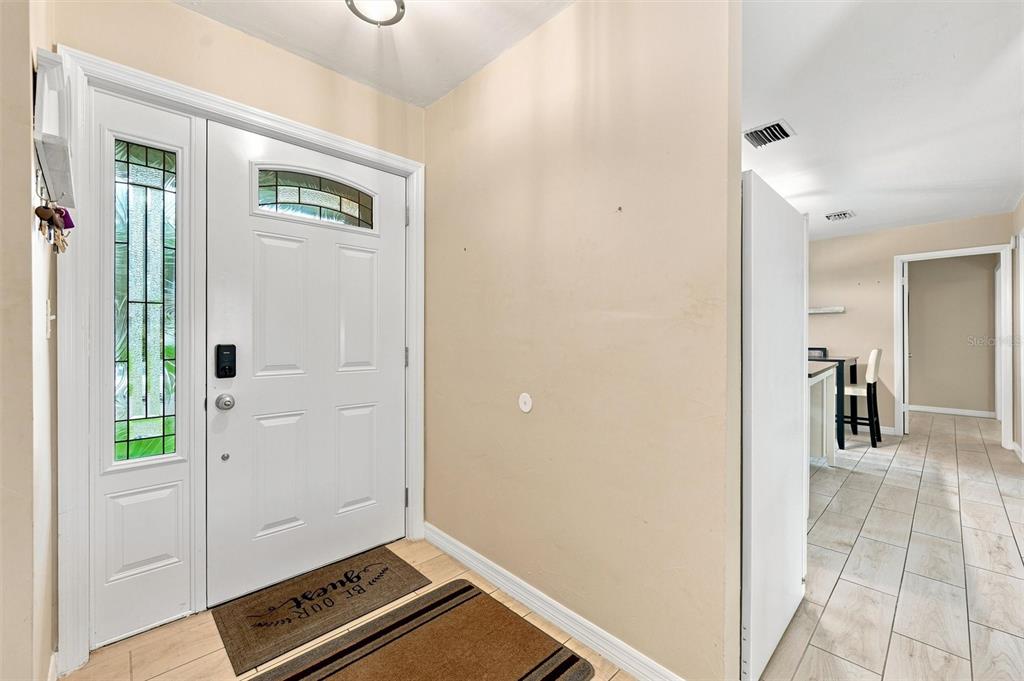 An entryway features a white front door, tiled floors, and a view into a hallway — 670 KIRKLAND CIRCLE, DUNEDIN, FL