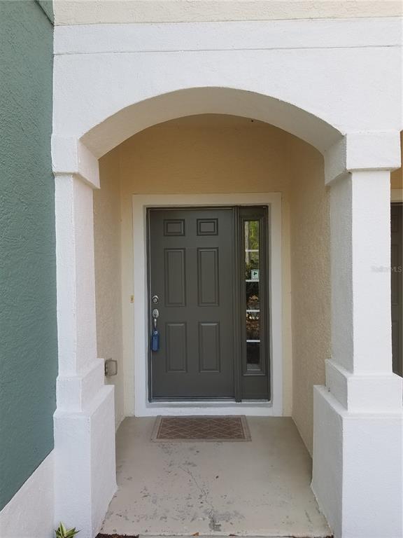 A dark gray front door with a side window sits under a white arched entryway — 4238 SW 50TH CIRCLE, OCALA, FL