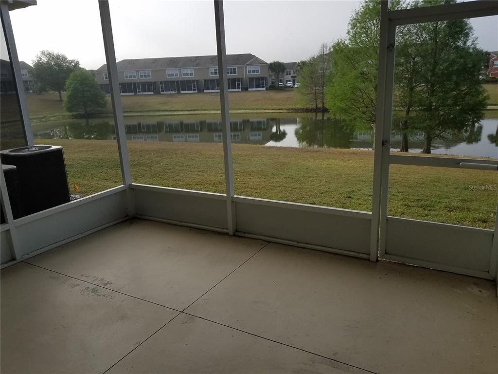 A screened-in concrete patio overlooks a pond and multi-story residential buildings — 4238 SW 50TH CIRCLE, OCALA, FL