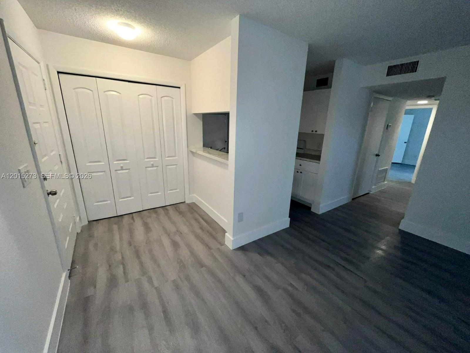 A room with gray wood-look flooring, a white closet, and a pass-through to a kitchen — 4561 W Mcnab Rd # 17, Pompano Beach FL 33069, POMPANO BEACH, FL
