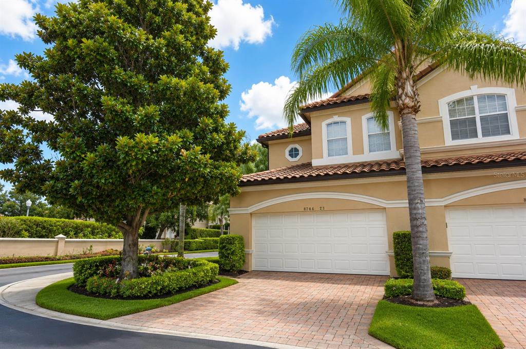 A two-story tan stucco townhouse features a white two-car garage and a palm tree — 8766 THE ESPLANADE UNIT 23, ORLANDO, FL