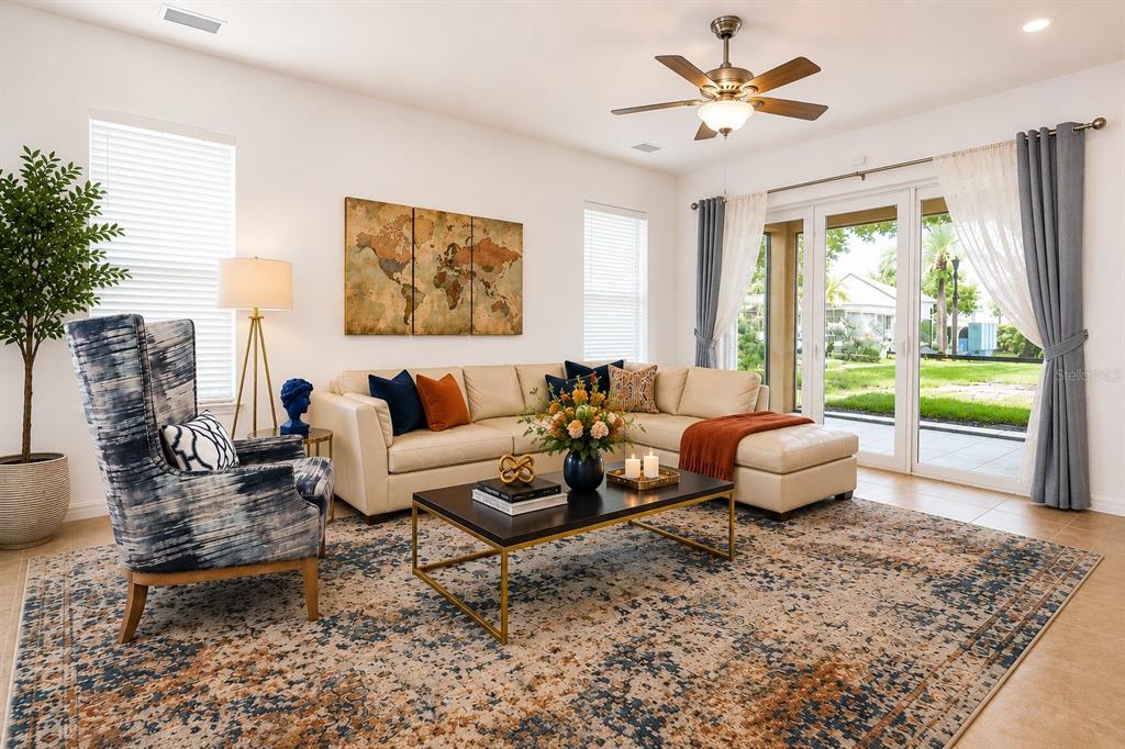 A living room features a beige sectional, patterned armchair, coffee table, and sliding glass doors — 8766 THE ESPLANADE UNIT 23, ORLANDO, FL