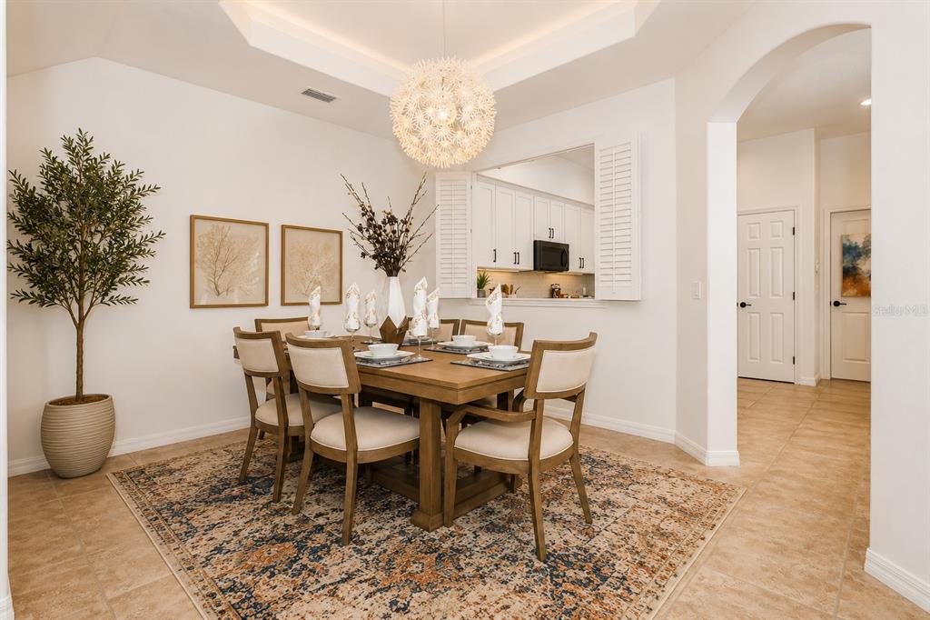 A dining room features a wooden table, upholstered chairs, a patterned rug, and a chandelier — 8766 THE ESPLANADE UNIT 23, ORLANDO, FL