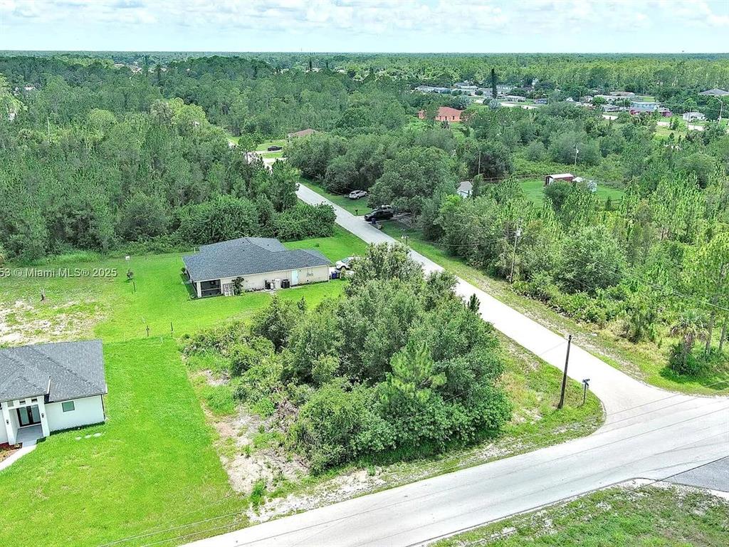 An aerial view shows a residential property with a house, lawn, and surrounding trees — 2500 E 10TH STREET, LEHIGH ACRES, FL